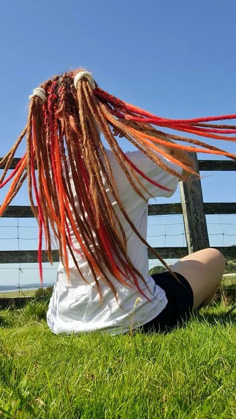 Lange rote, orange und blonde Dreadlock-Extensions im Freien